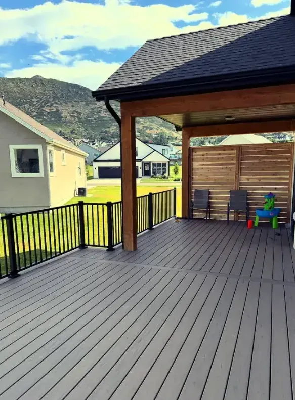 Covered custom deck with black railing by Frame Platinum LLC