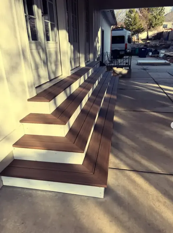 Wide front entry stairs with brown treads and white risers by Frame Platinum LLC